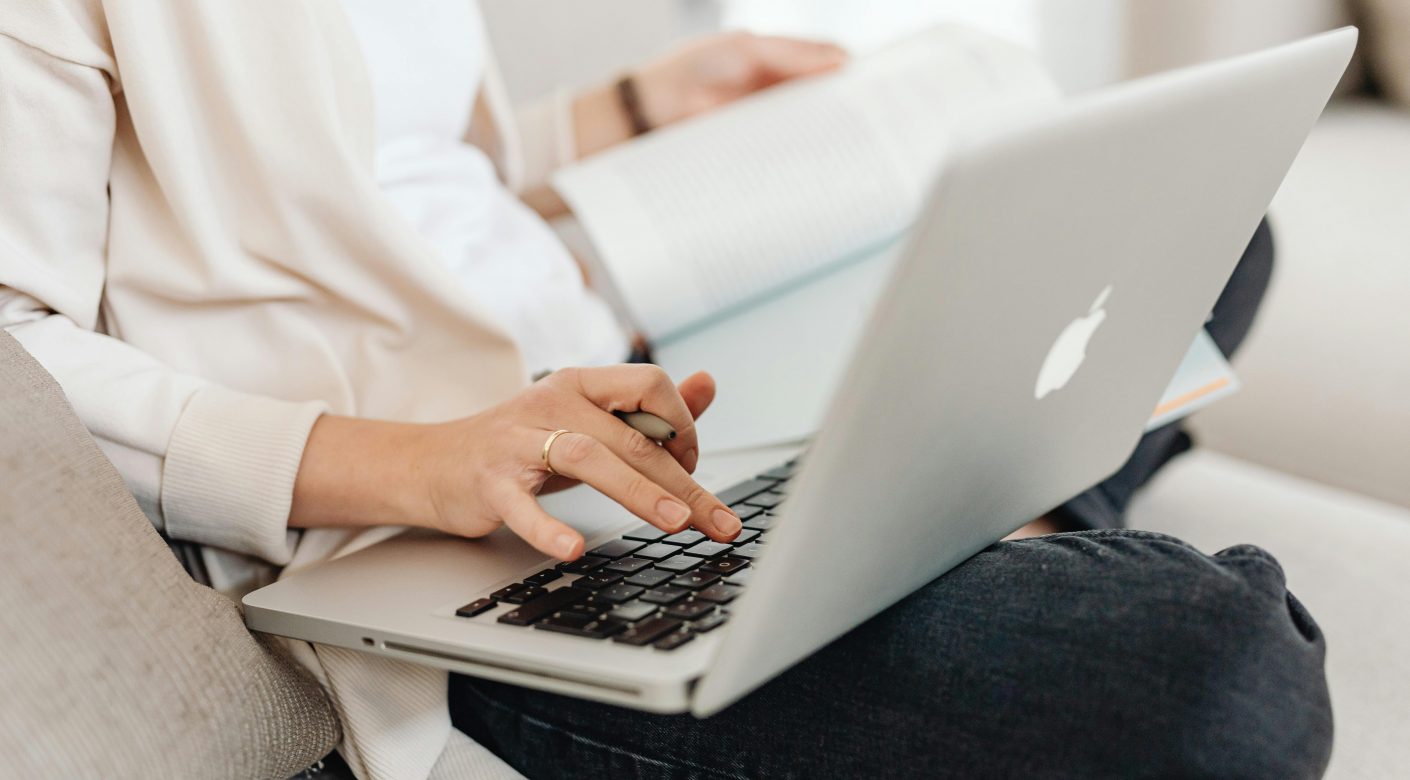 kobieta siedzaca i sprawdzajaca informacje na laptopie