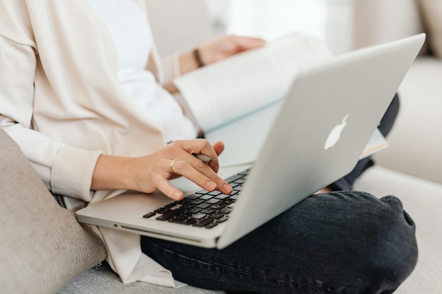kobieta siedzaca i sprawdzajaca informacje na laptopie