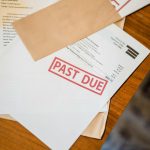 Zdjęcie pokazuje leżace na stole dokuemnty i niezapłacone rachinki co nawiązuje do długó małżonka w czasie rozwod UK.